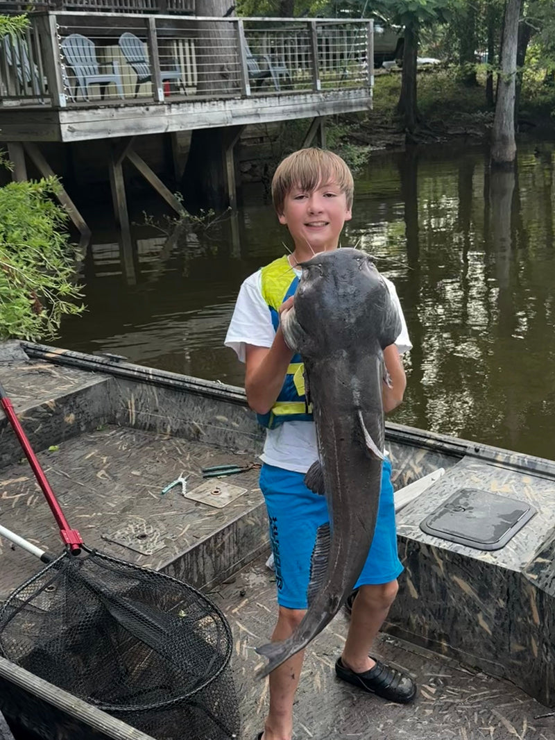 Child holding a large fish on a boat near a dock